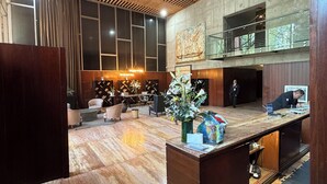 Un hall d’entrée avec un plafond en bois, un comptoir d’accueil, un espace salon et une grande fenêtre.