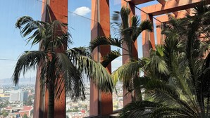 Un espace extérieur moderne, aménagé pour se détendre, avec vue sur le paysage urbain, comprenant une terrasse en bois et des plantes en pot.