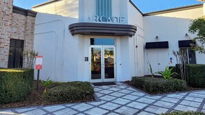Un bâtiment doté d’une façade moderne, d’une entrée imposante et d’une enseigne sur laquelle on peut lire « ARCADE ».