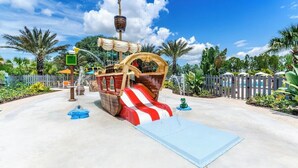 Un espace de jeux aquatiques sur le thème des pirates, avec une structure en forme de navire, des toboggans et une petite piscine.