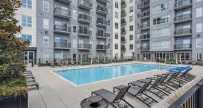 A modern apartment building with a swimming pool, outdoor seating, and balconies. - Luxury High-Rise, Walk to Broadway, Pool + Sky Lounge, coffee essentials (Nashville)