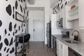 A modern kitchen with white cabinets, a stainless steel refrigerator, and a granite countertop. - Luxury High-Rise, Walk to Broadway, Pool + Sky Lounge, coffee essentials (Nashville)