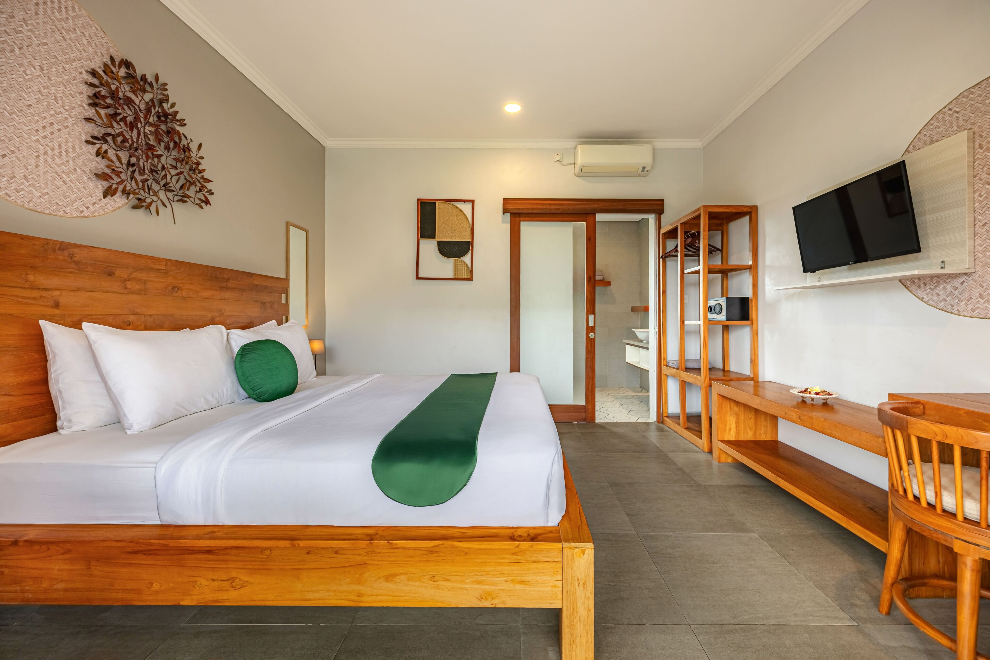 A hotel room with a wooden bed, a desk, a chair, a TV mounted on the wall, and a mirror.