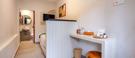 A compact hotel room with a kitchenette, a small seating area, and a bathroom with a shower and toilet.