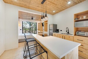 A modern kitchen with a large island, wooden cabinets, and a view of the outdoors. - Spacious 4-Bed Home with Stunning Outdoor Living (Playa Flamingo)