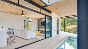 Ein modernes Interieur mit Pool, weißen Möbeln und großen Fenstern.