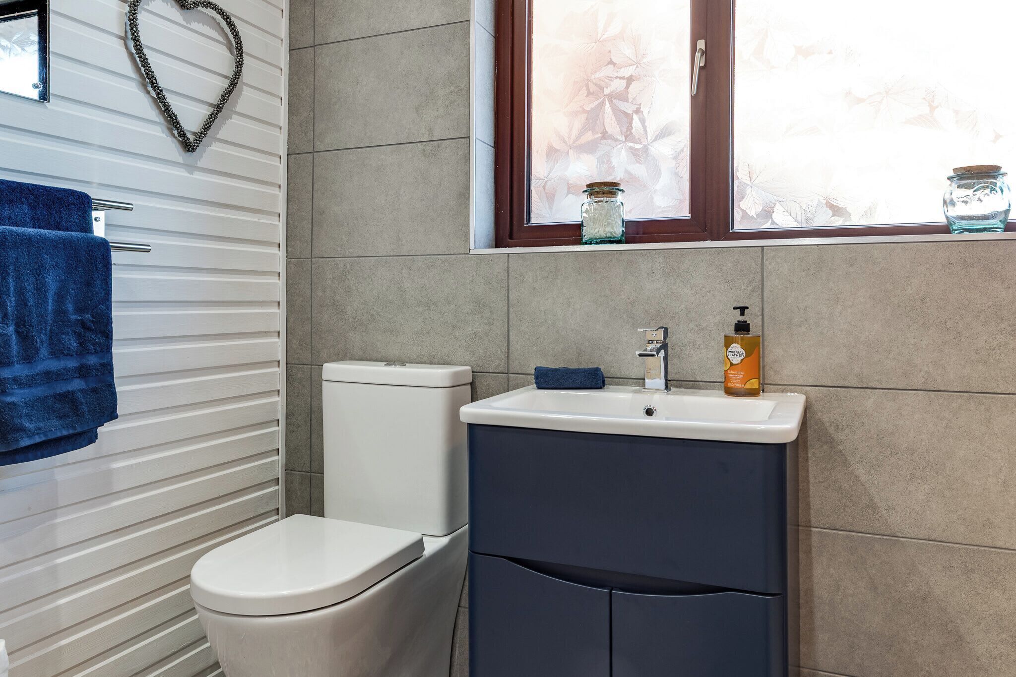 A bathroom with a toilet, a sink, and a window with a view of foliage.