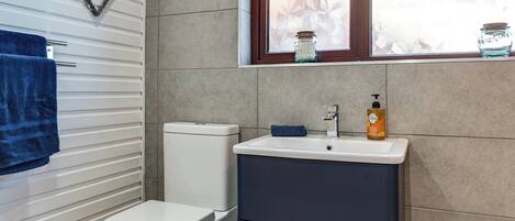 A bathroom with a toilet, a sink, and a window with a view of foliage.