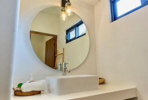 A bathroom with a round mirror, white sink, and a small window. - New Beachfront Suites 2nd Floor Complete Beachfront, Beautiful Ocean View (El Sargento)