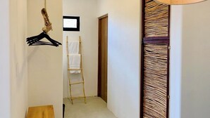 Un passadís amb una banca de fusta, una perxa penjant, una escala i una porta de vidre trenat.