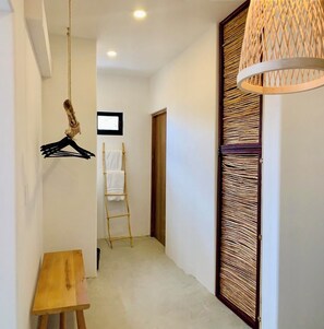 A hallway with a wooden bench, a hanging coat rack, a ladder, and a woven door. - New Beachfront Suites 2nd Floor Complete Beachfront, Beautiful Ocean View (El Sargento)