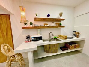 A compact kitchen with a microwave, sink, and various storage shelves. - New Beachfront Suites 2nd Floor Complete Beachfront, Beautiful Ocean View (El Sargento)