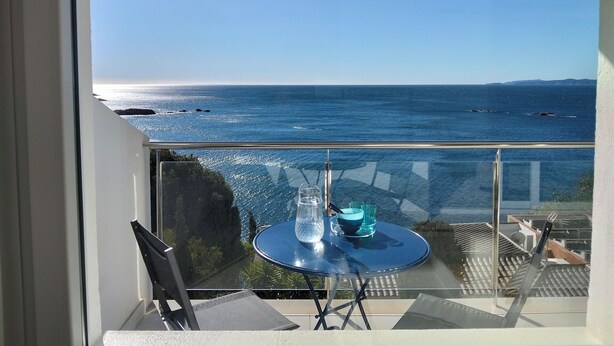 En balkon med et bord, stole og havudsigt.