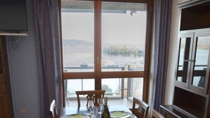 Een eethoek met een tafel voor vier personen, een televisie en uitzicht op een waterlichaam.