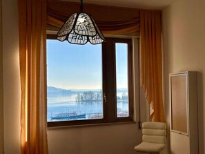 Ein Zimmer mit einem großen Fenster, einem Sessel und einem Schrank.