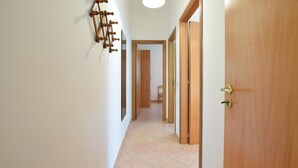 Un pasillo con puertas de madera y suelo de baldosas.
