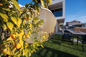 Un espacio exterior moderno con una mesa y sillas de madera, rodeado de un césped cuidado y una valla de madera.