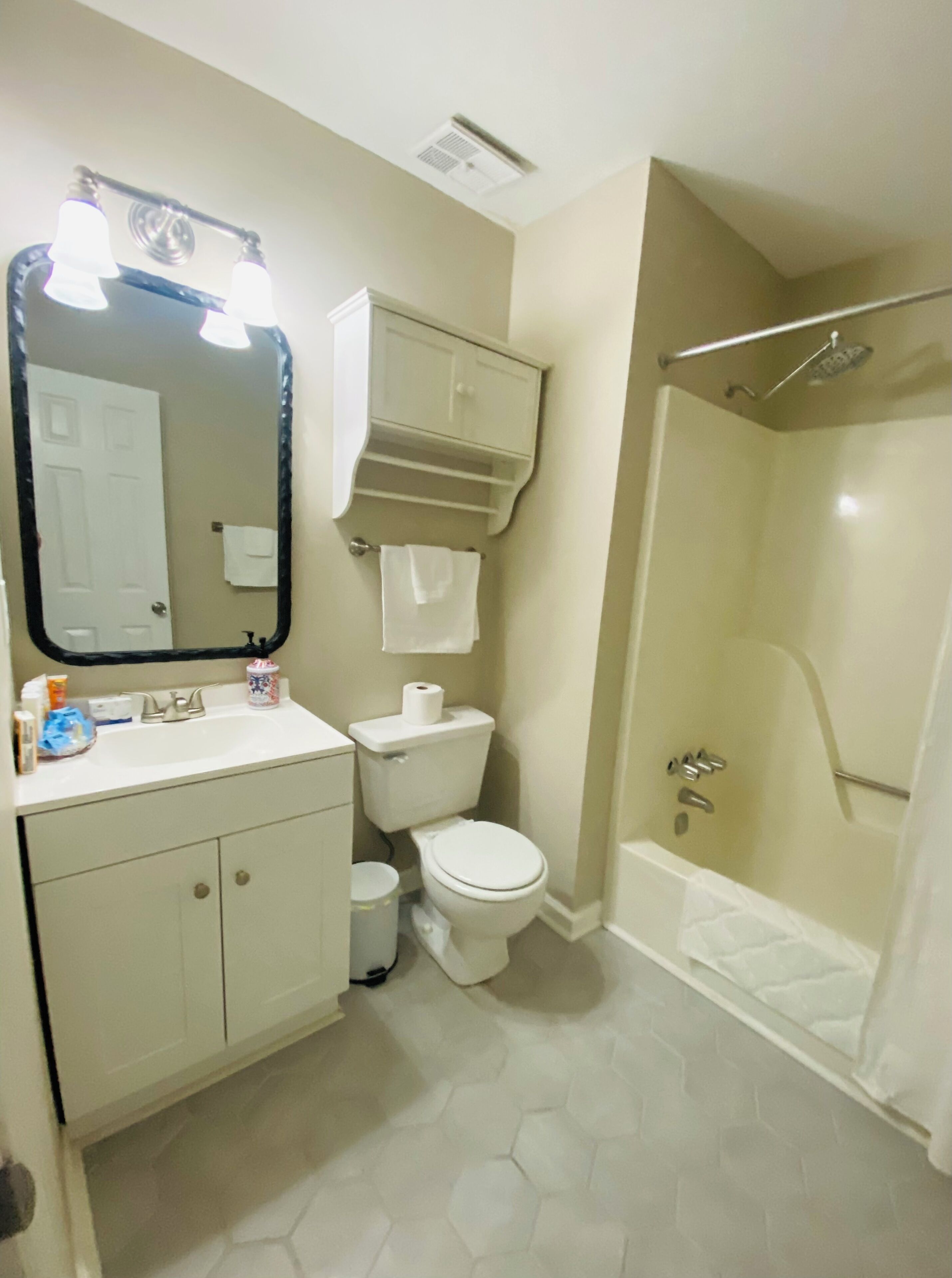 A bathroom with a toilet, sink, mirror, and shower.