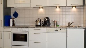 A modern kitchen with white cabinets, a built-in oven, a kettle, and a coffee maker. - La Solina Lunghin by Interhome (Maloja)