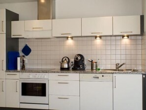 A modern kitchen with white cabinets, a built-in oven, a kettle, and a coffee maker. - La Solina Lunghin by Interhome (Maloja)