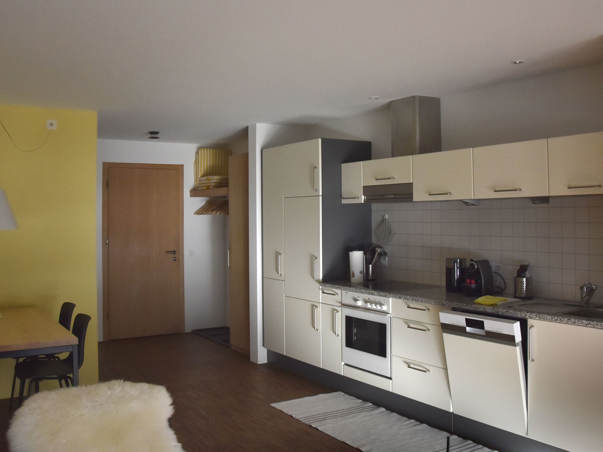 A compact kitchen with white cabinets, a built-in oven, and a coffee maker.