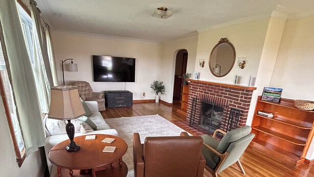 A living room with a fireplace, a television, a sofa, and a dining table.