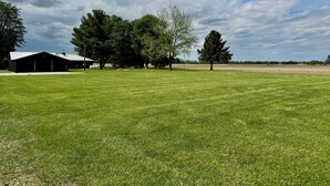 A grassy field with a barn and trees.