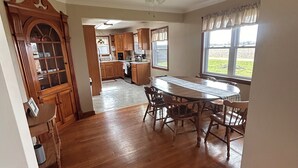 A spacious kitchen with wooden cabinets, a dining table with chairs, and a ceiling fan.