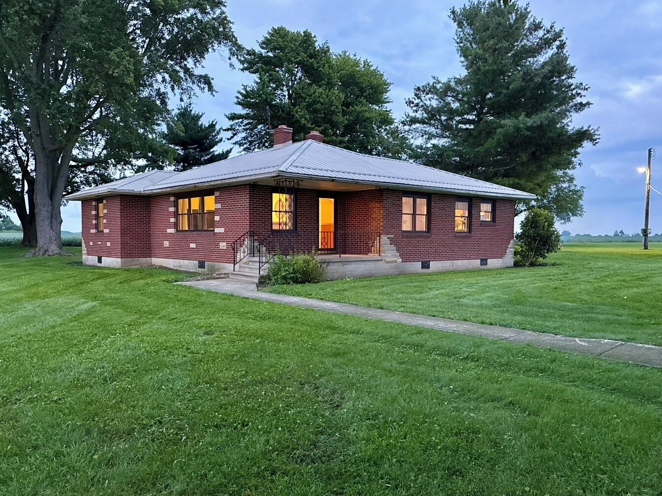 A single-story brick building with a gabled roof, a front porch, and a small front yard.