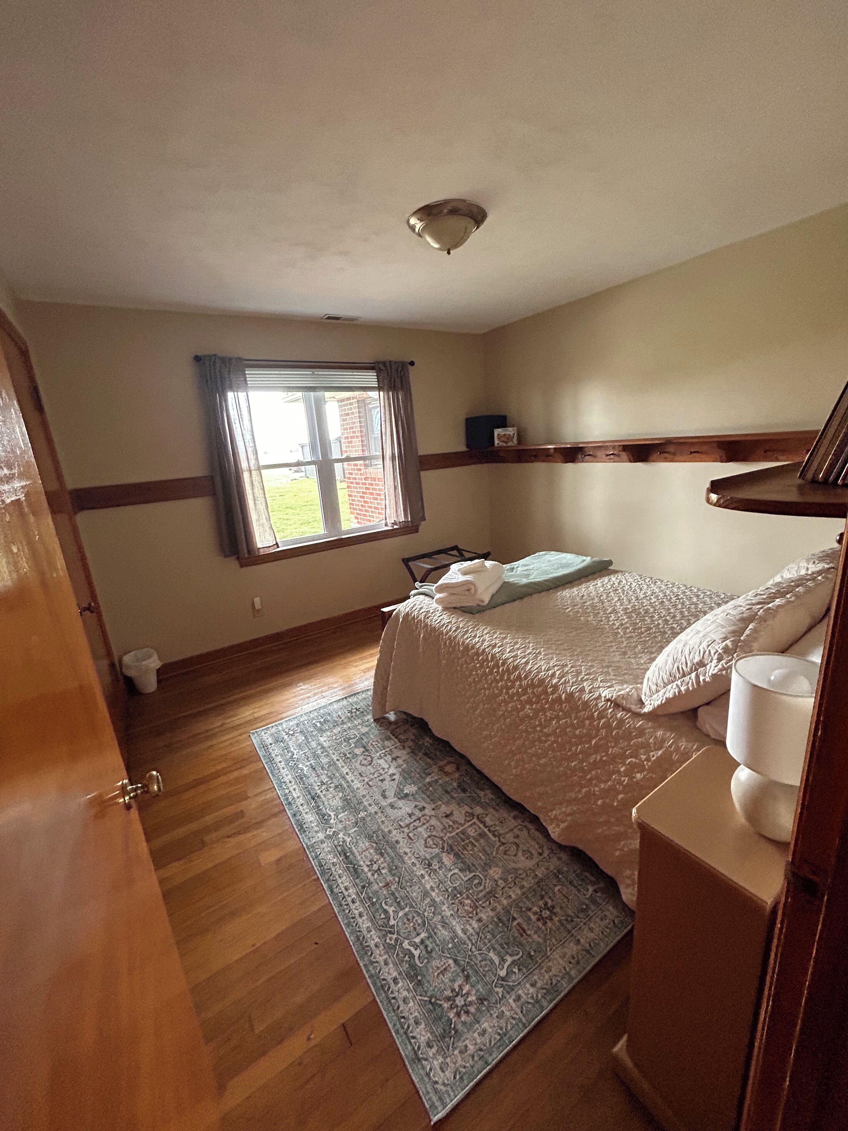 Une chambre à coucher avec un lit, une fenêtre, une porte et un tapis.