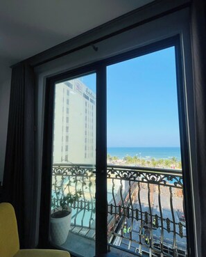 A room with a large window overlooking a beach and a construction site. - Emily Beach Hotel & Apartment (Da Nang)