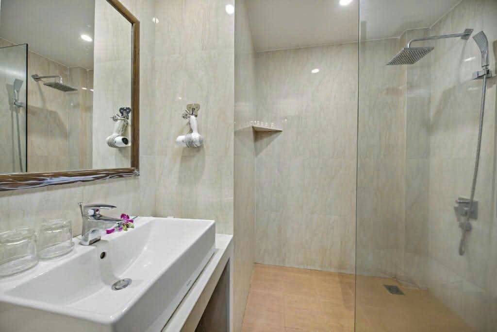 A modern bathroom with a glass shower enclosure, a white sink, and a mirror.