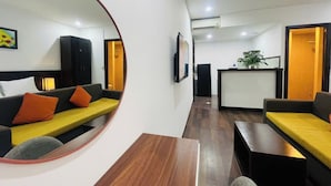 Un hall d’hôtel moderne avec un canapé, un grand miroir rond, un comptoir d’accueil et une plante.