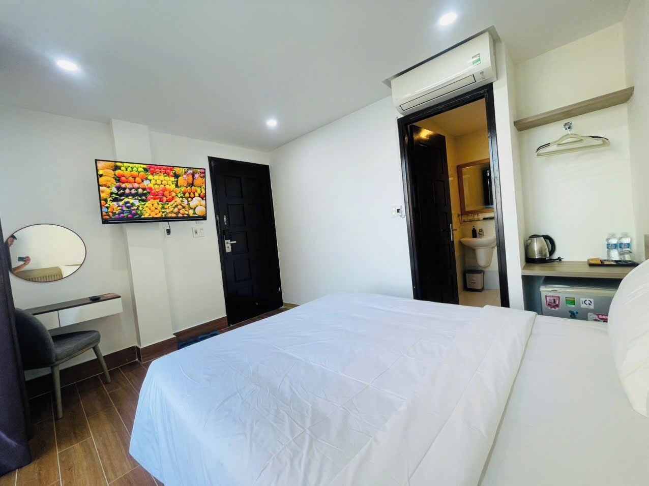 Une chambre d’hôtel équipée d’un lit, d’un bureau, d’une chaise, d’un miroir, d’un téléviseur fixé au mur et d’un coin cuisine.