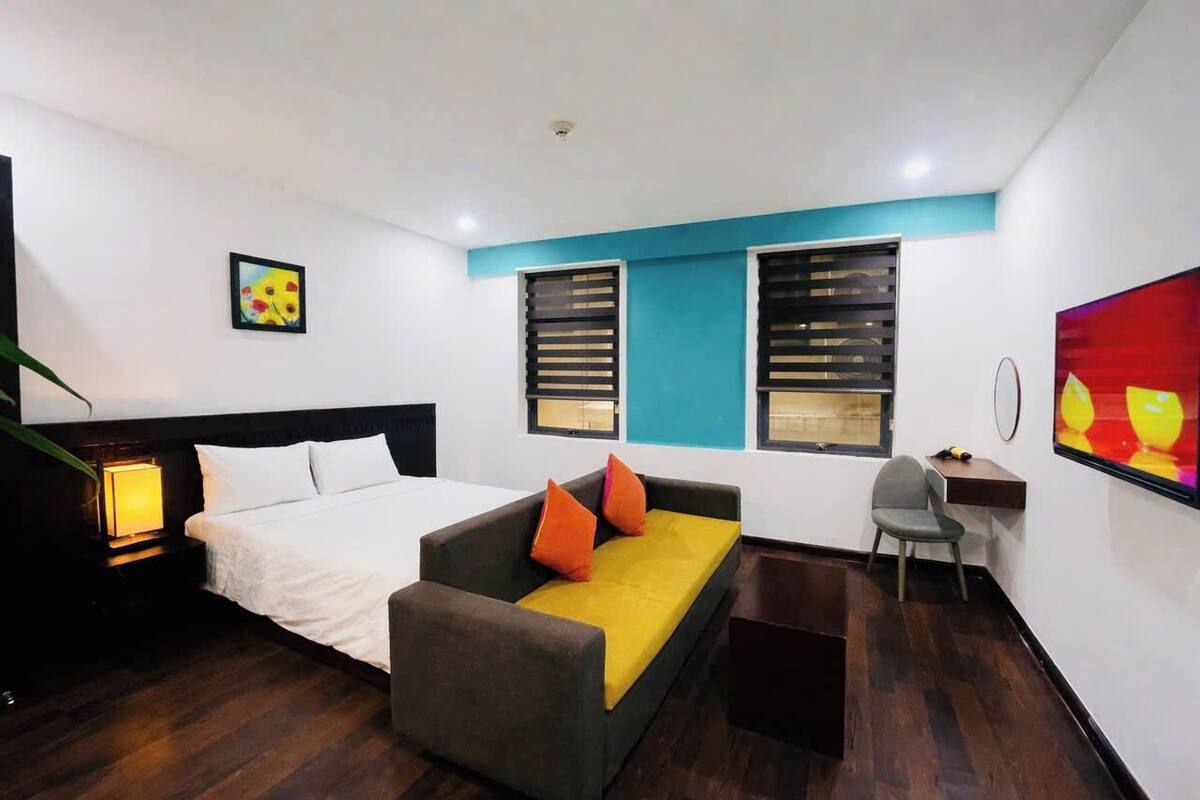 A hotel room with a bed, a sofa, a desk, and a chair.