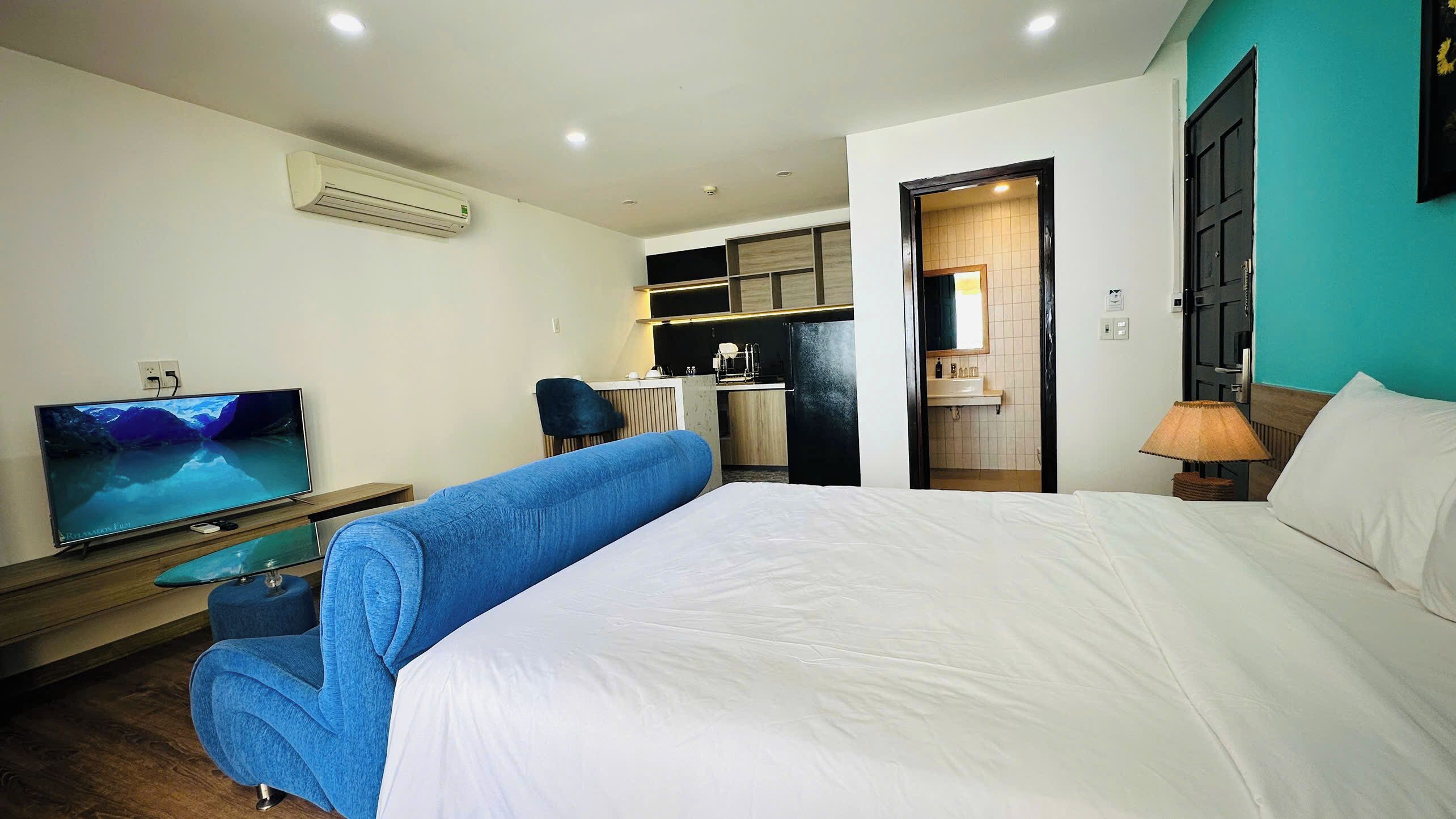 Una habitación de hotel con cama, televisión, escritorio y kitchenette.