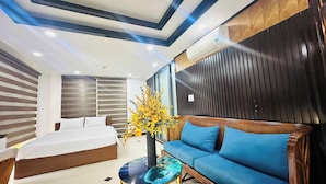 Une chambre d’hôtel moderne équipée d’un lit, d’un canapé, d’une table basse en verre, d’un vase décoratif et d’un appareil de climatisation.