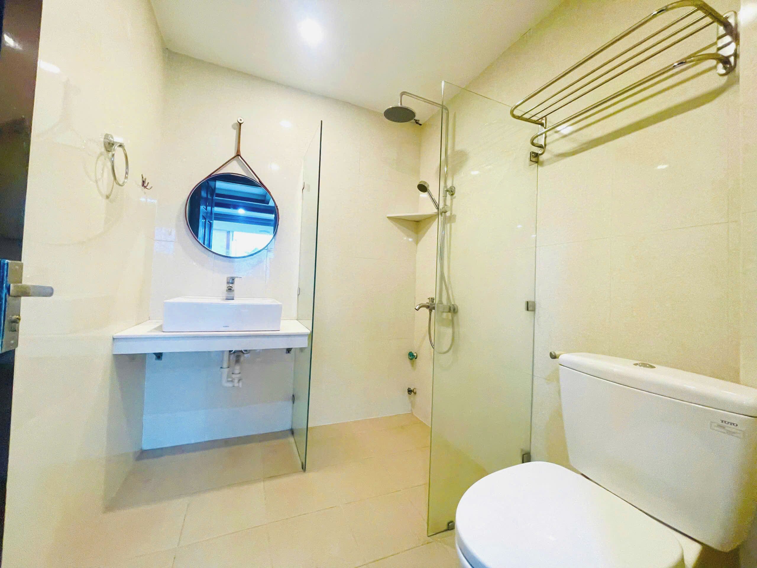 A modern bathroom with a glass shower enclosure, a toilet, and a sink with a mirror.