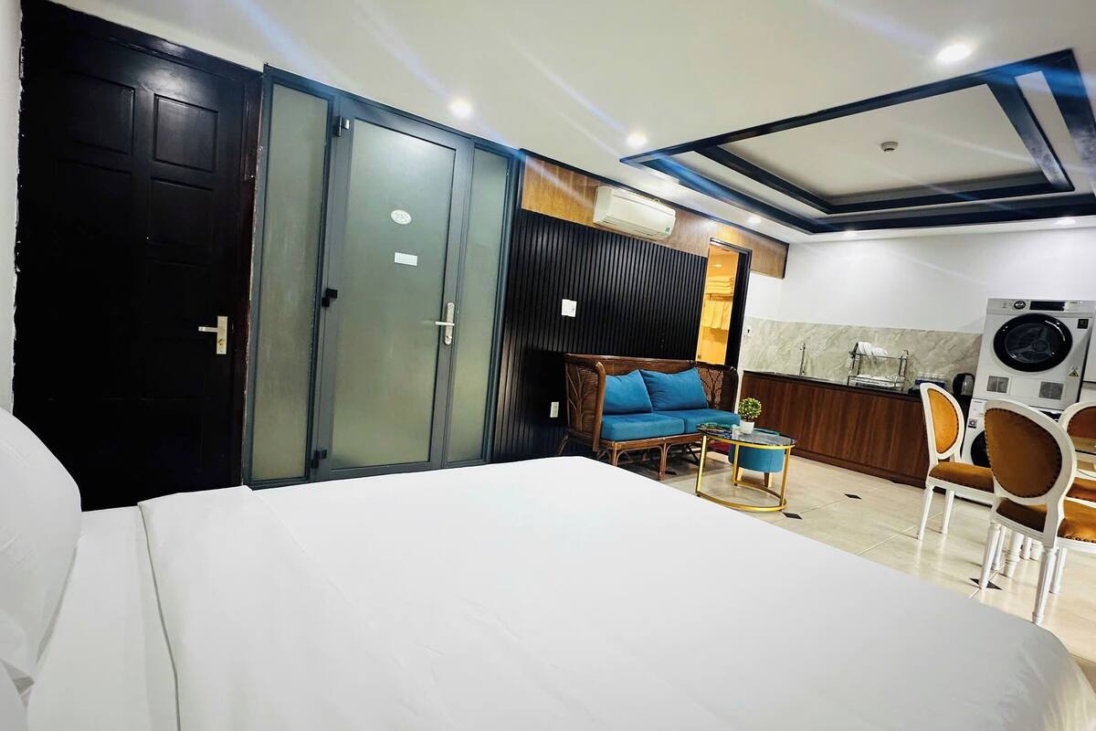 A hotel room with a bed, a sofa, a small table, and a kitchenette area.