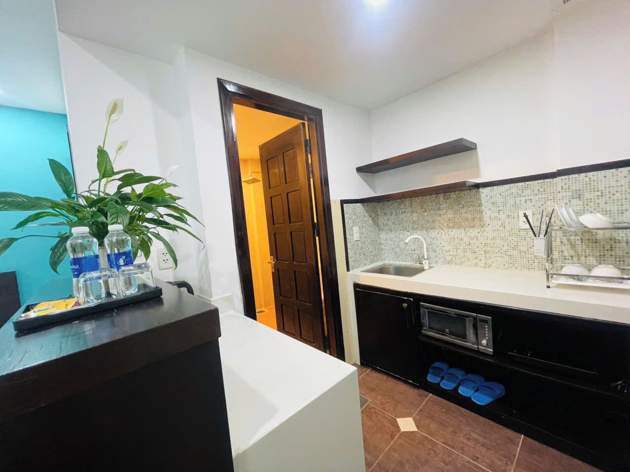 Cocina compacta con lavabo, microondas y armarios de almacenamiento.