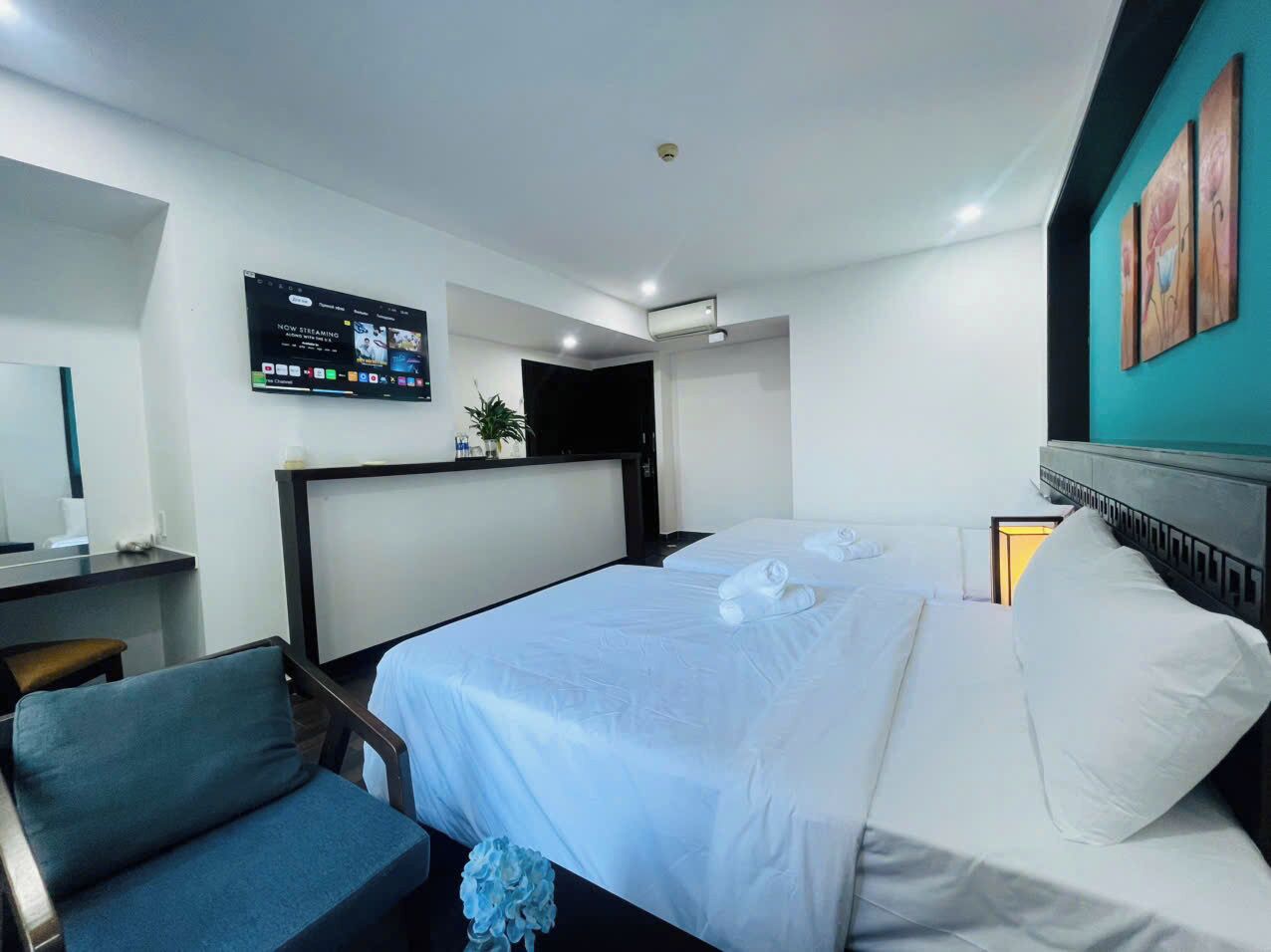 A hotel room with a bed, a desk, a chair, and a TV mounted on the wall.