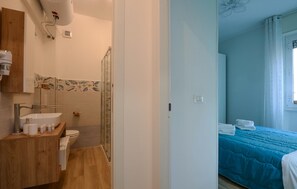 Et badeværelse med vask, toilet og bruser.