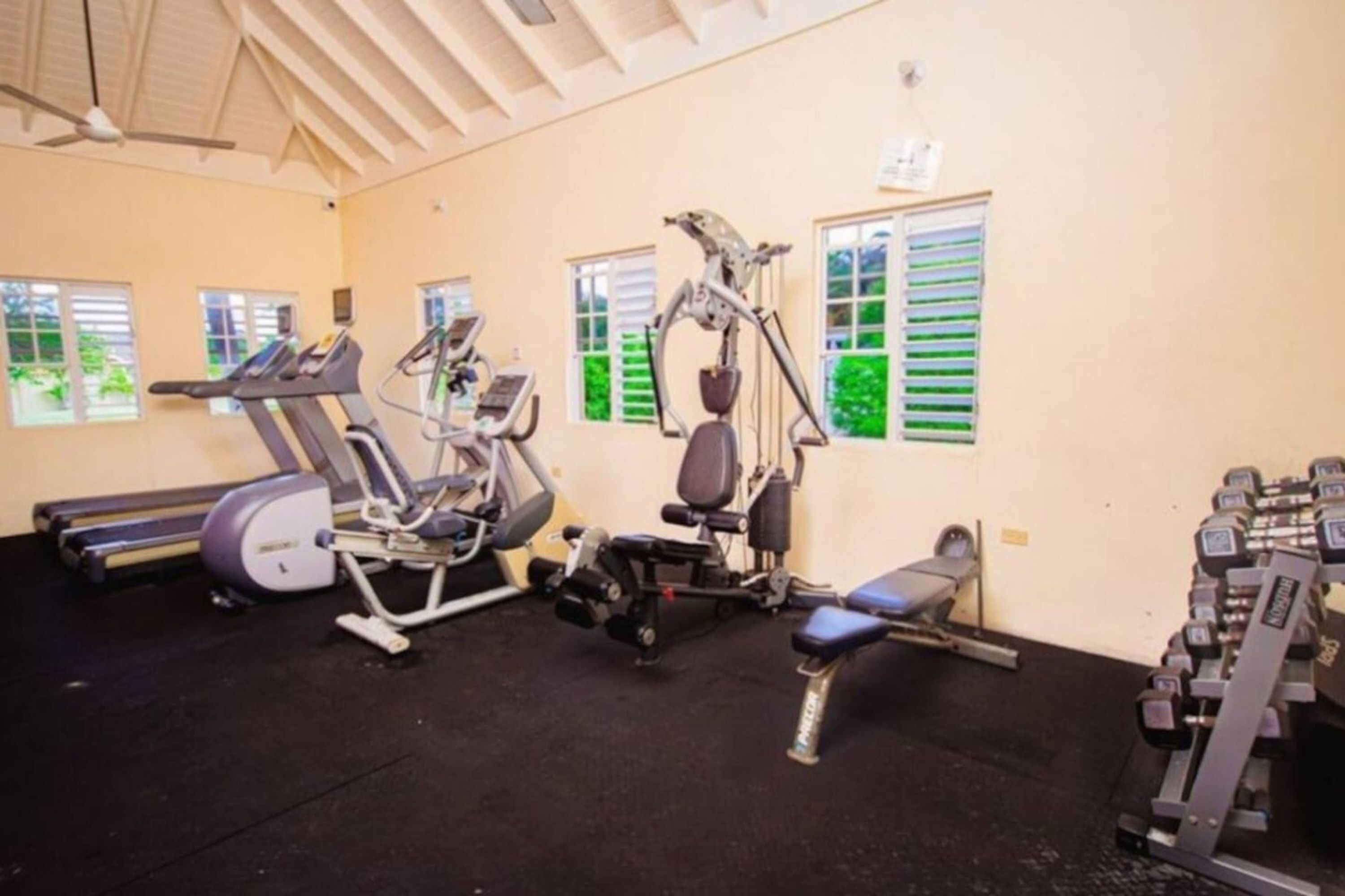Et fitnesscenter med løbebånd, crosstrainere, bænkpres og håndvægte.