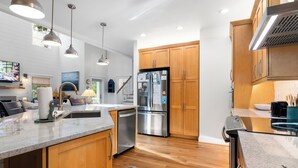 A modern kitchen with wooden cabinets, stainless steel appliances, and pendant lighting. - "Slow Your Roll" is a pet-friendly, five-bedroom, 4.5-bath Maritime Forest (Bald Head Island)