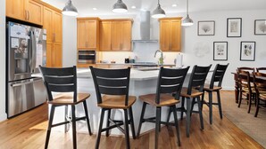 A modern kitchen with wooden cabinets, stainless steel appliances, and a central island with bar stools. - "Slow Your Roll" is a pet-friendly, five-bedroom, 4.5-bath Maritime Forest (Bald Head Island)