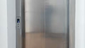 En moderne elevator med metalfinish og et digitalt kontrolpanel på venstre side.