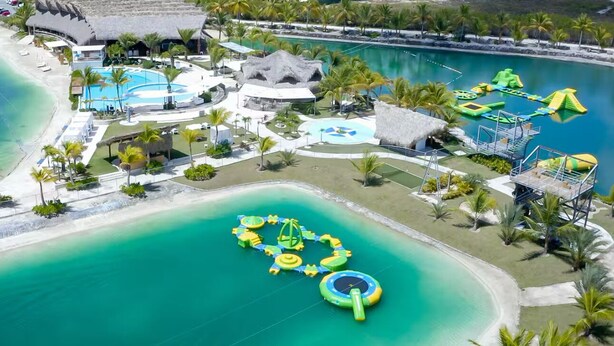 Oversigtsbillede af et resort med en stor swimmingpool, vandrutsjebaner og et strandområde.