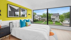 Een moderne slaapkamer met een groot raam, een bed met witte beddengoed en een felgele accentmuur.