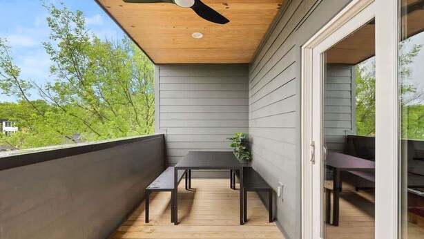 Ein Balkon mit Deckenventilator, Tisch und Stühlen mit Blick auf eine grüne Landschaft.