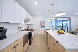 A modern kitchen with white cabinets, a black stove, and a large window with curtains. - Hyve-Anthem-Private Balconies-Walk to Broadway (Nashville)